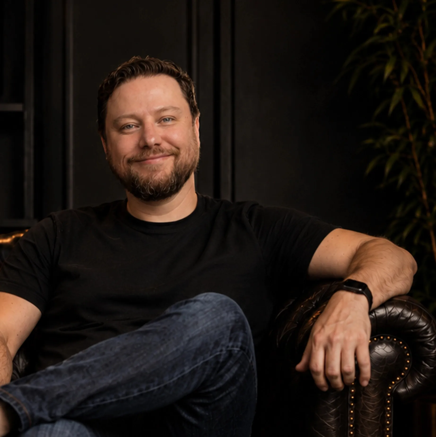 Will Siscar seated in a leather chair in his studio